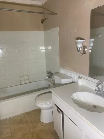a bathroom with a granite countertop sink a toilet a mirror and bathtub