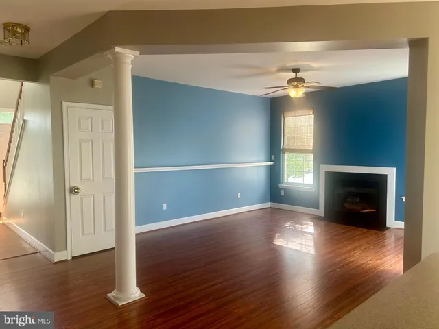 an empty room with wooden floor fireplace and windows