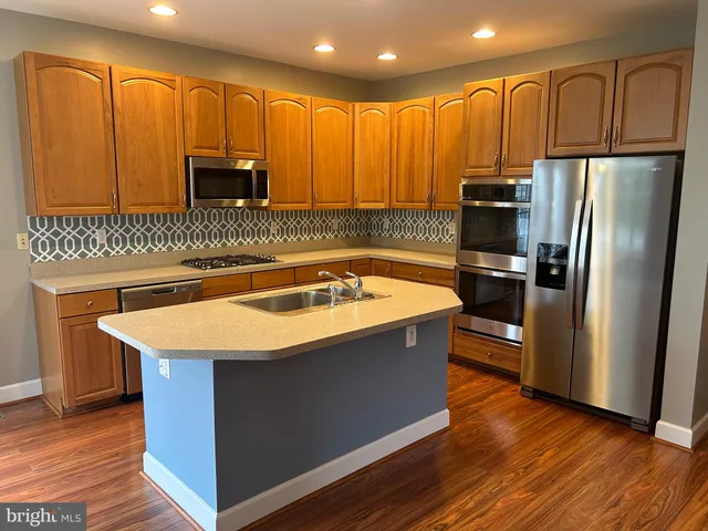 a kitchen with stainless steel appliances granite countertop a sink a stove and a refrigerator