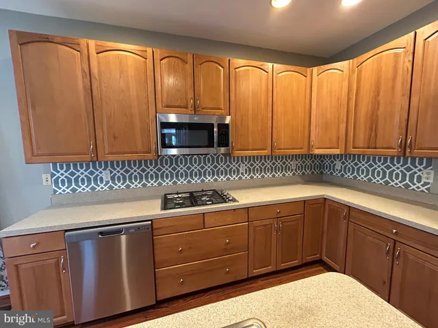 a kitchen with stainless steel appliances granite countertop a sink window and cabinets