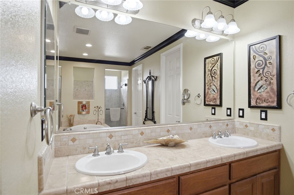 4822 Durant Way Merced, CA 95348 - Photo 31 of 48 a bathroom with double vanity sinks a vanity a lamp and a mirror