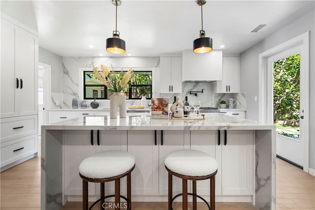 a large kitchen with stainless steel appliances a sink a stove and cabinets
