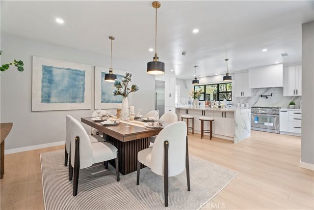 a kitchen with stainless steel appliances kitchen island granite countertop a stove a sink a dining table and chairs with wooden floor