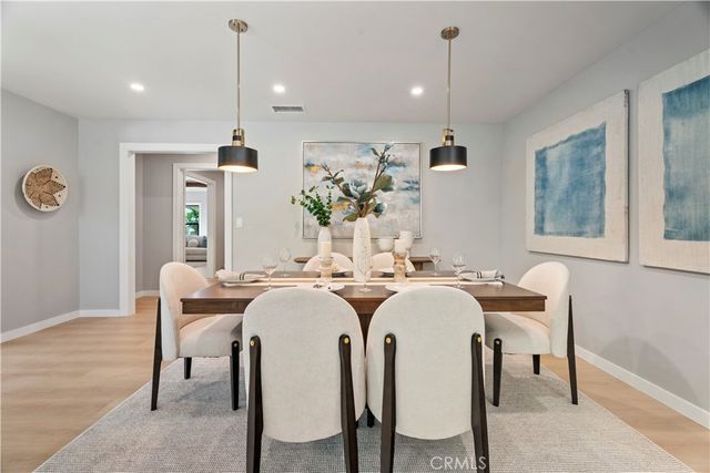 a kitchen with stainless steel appliances granite countertop a sink a stove a dining table and chairs