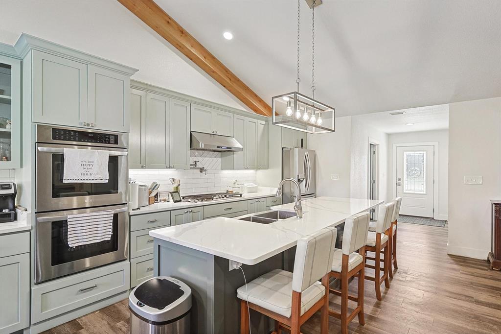 1161 Lynn Creek Road Jacksboro, TX 76458 - Photo 11 of 40 Kitchen featuring sink, lofted ceiling with beams, a kitchen bar, a kitchen island with sink, and appliances with stainless steel finishes