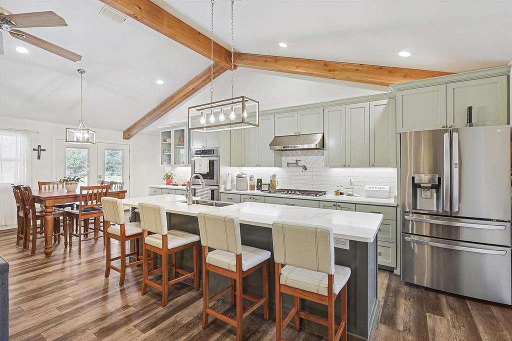 1161 Lynn Creek Road Jacksboro, TX 76458 - Photo 15 of 40 Kitchen featuring vaulted ceiling with beams, stainless steel appliances, hanging light fixtures, and an island with sink