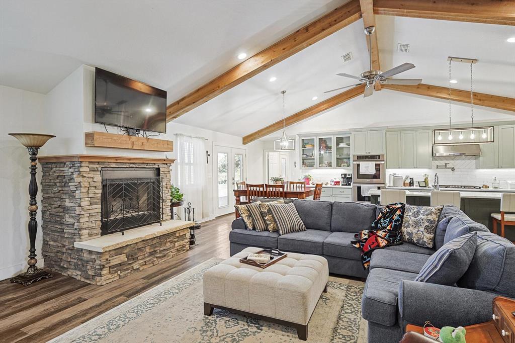 1161 Lynn Creek Road Jacksboro, TX 76458 - Photo 17 of 40 Living room featuring wood-type flooring, lofted ceiling with beams, a stone fireplace, and ceiling fan