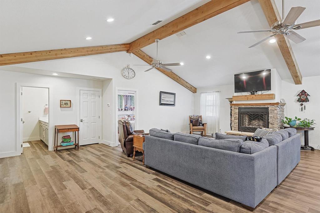 1161 Lynn Creek Road Jacksboro, TX 76458 - Photo 18 of 40 Living room featuring a stone fireplace, ceiling fan, lofted ceiling with beams, and light hardwood / wood-style floors