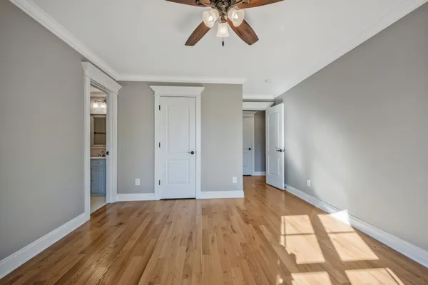 a view of empty room with wooden floor and fan