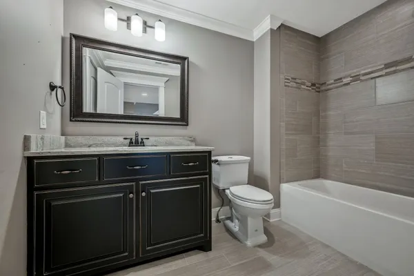 a bathroom with a toilet sink vanity granite and bathtub