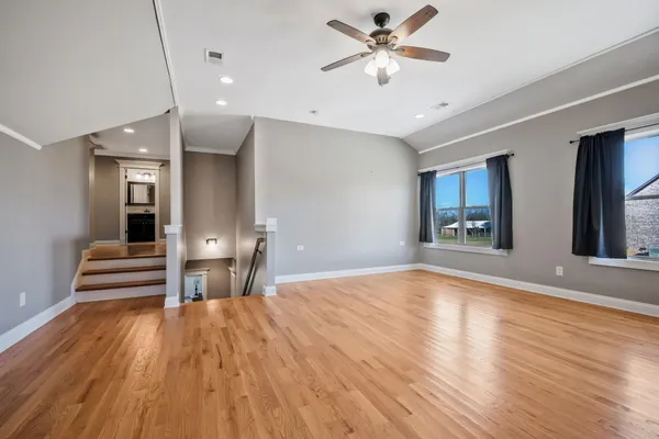 a view of empty room with wooden floor and fan