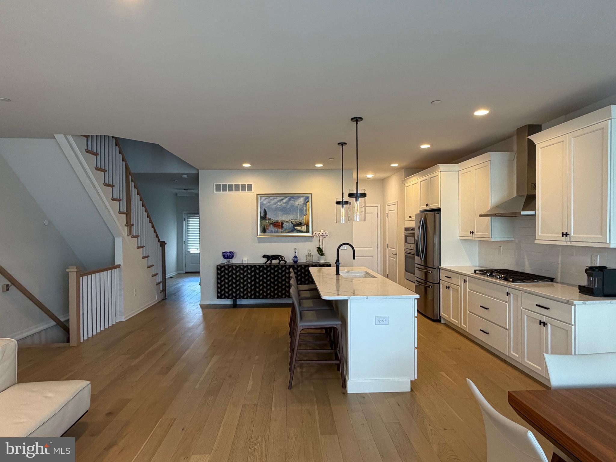 12 Spring Mill Drive Ivyland, PA 18974 - Photo 7 of 25 a large white kitchen with wooden floors and stainless steel appliances