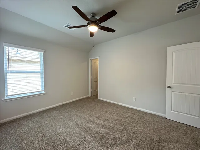an empty room with a ceiling fan and window