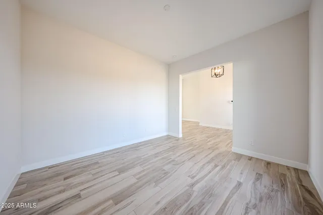 a view of empty room with wooden floor and kitchen