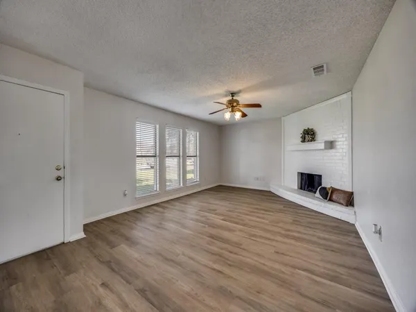 a view of an empty room with a window and fireplace