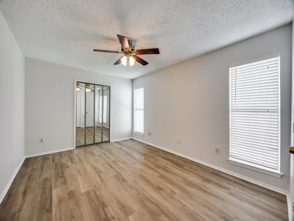 a view of empty room with wooden floor and fan