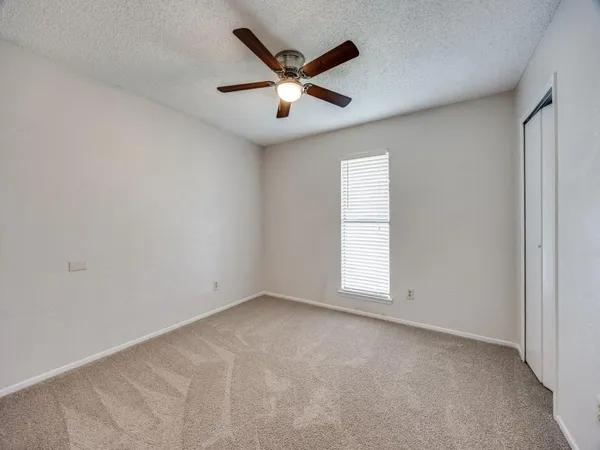 an empty room with window and ceiling fan