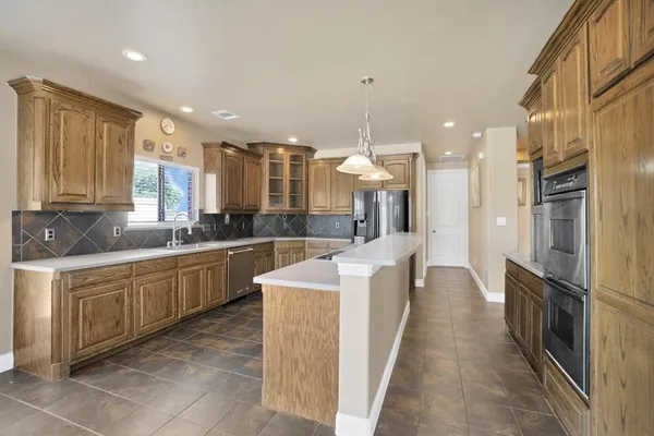 a large kitchen with stainless steel appliances lots of counter space and a sink