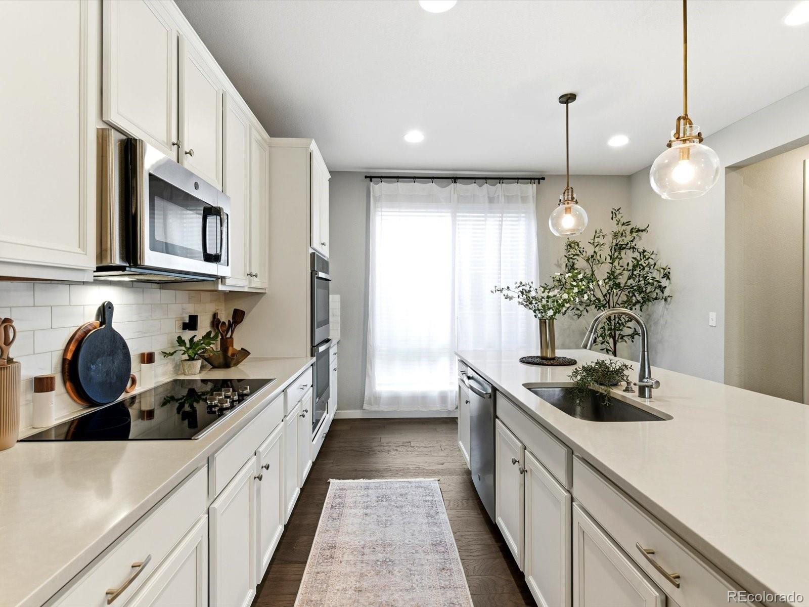 8338 Rivulet Point Highlands Ranch, CO 80129 - Photo 13 of 50 a kitchen with kitchen island granite countertop a sink and refrigerator