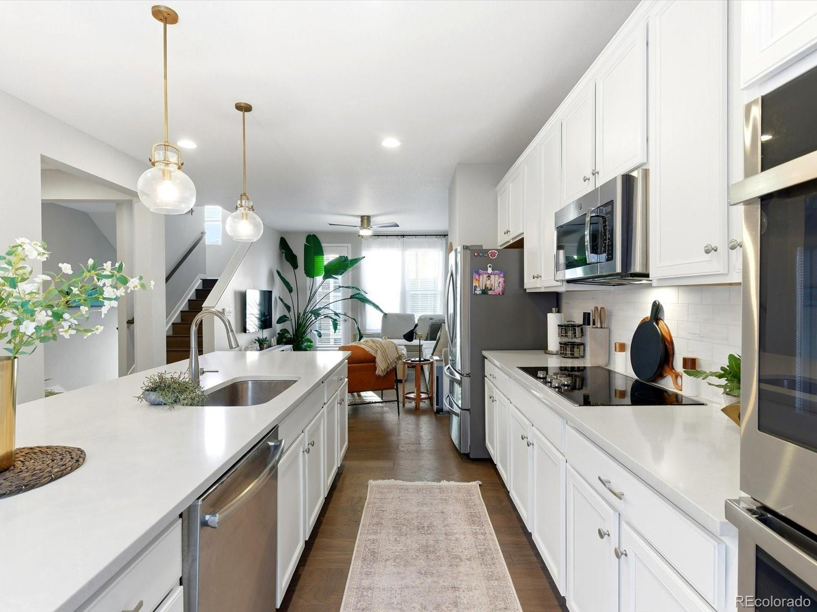 8338 Rivulet Point Highlands Ranch, CO 80129 - Photo 14 of 50 a kitchen with kitchen island granite countertop a sink a counter space and stainless steel appliances