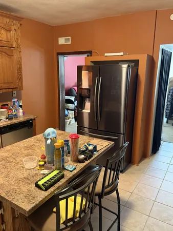 a kitchen with stainless steel appliances granite countertop a refrigerator a stove a sink a dining table and chairs