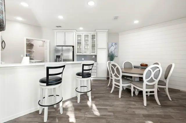 a kitchen with stainless steel appliances granite countertop a refrigerator a stove a sink dishwasher and white cabinets with wooden floor