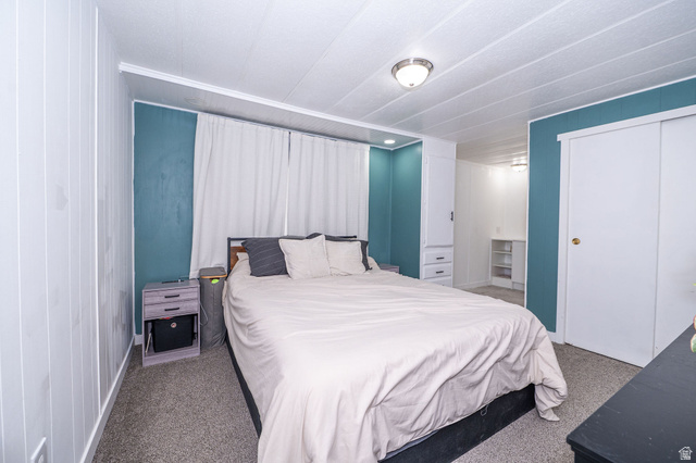 2600 North Hill Field Road, Unit 5 Layton, UT 84041 - Photo 14 of 33 Carpeted bedroom with a built-in wardrobe, sliding closet doors, a semi-flush ceiling light fixture, and vertical paneling on one wall