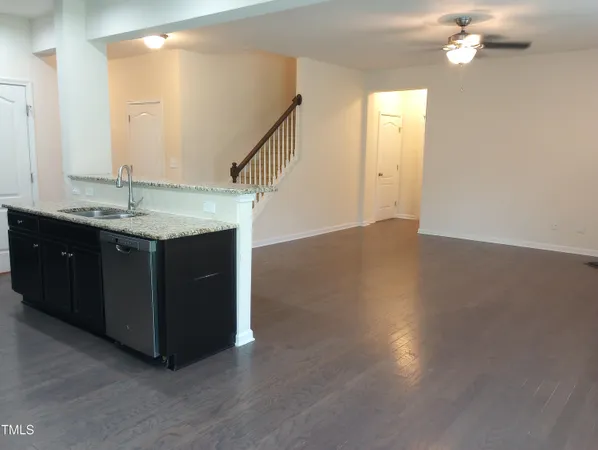an empty room with wooden floor chandelier and windows