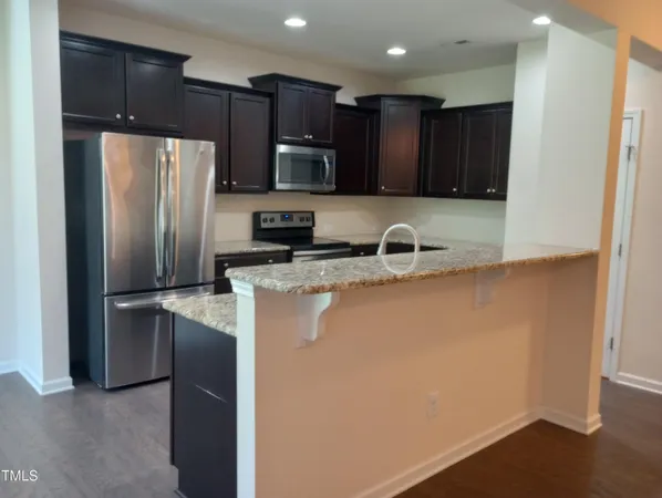 an open kitchen with kitchen island a sink wooden floor and a large window