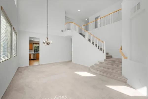 an empty room with windows and chandelier fan