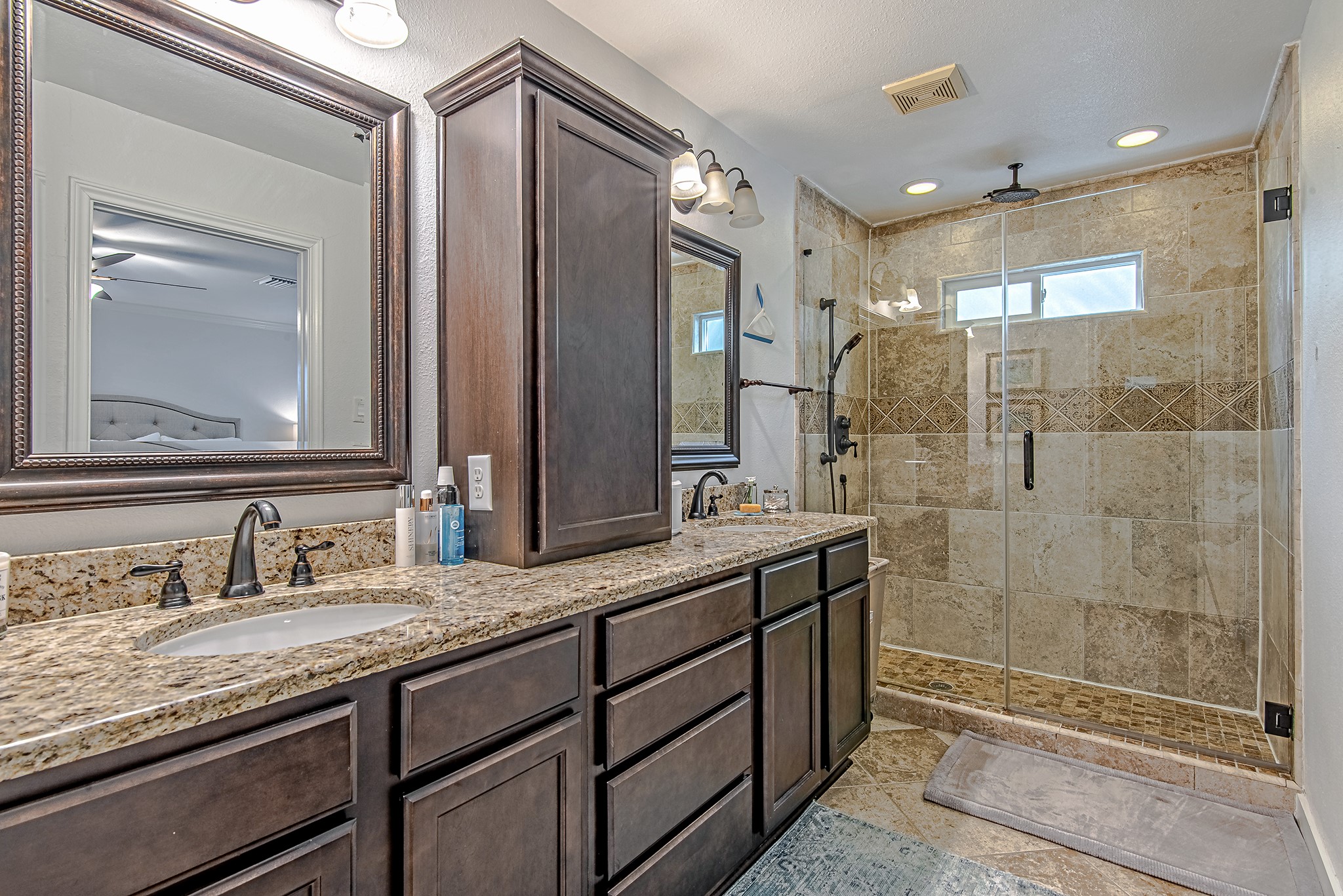 520 West 30th Street Houston, TX 77018 - Photo 17 of 28 The primary ensuite bathroom features a spacious double vanity with granite countertops and a large, beautifully tiled walk-in shower with a overhead rain shower head and a handheld shower head. The neutral tones and elegant finishes create a spa-like atmosphere, offering both style and functionality.