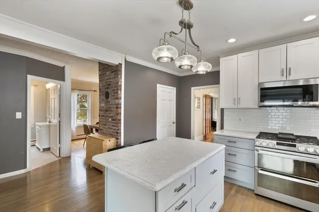 a kitchen with stainless steel appliances granite countertop a stove oven a refrigerator cabinets and wooden floor