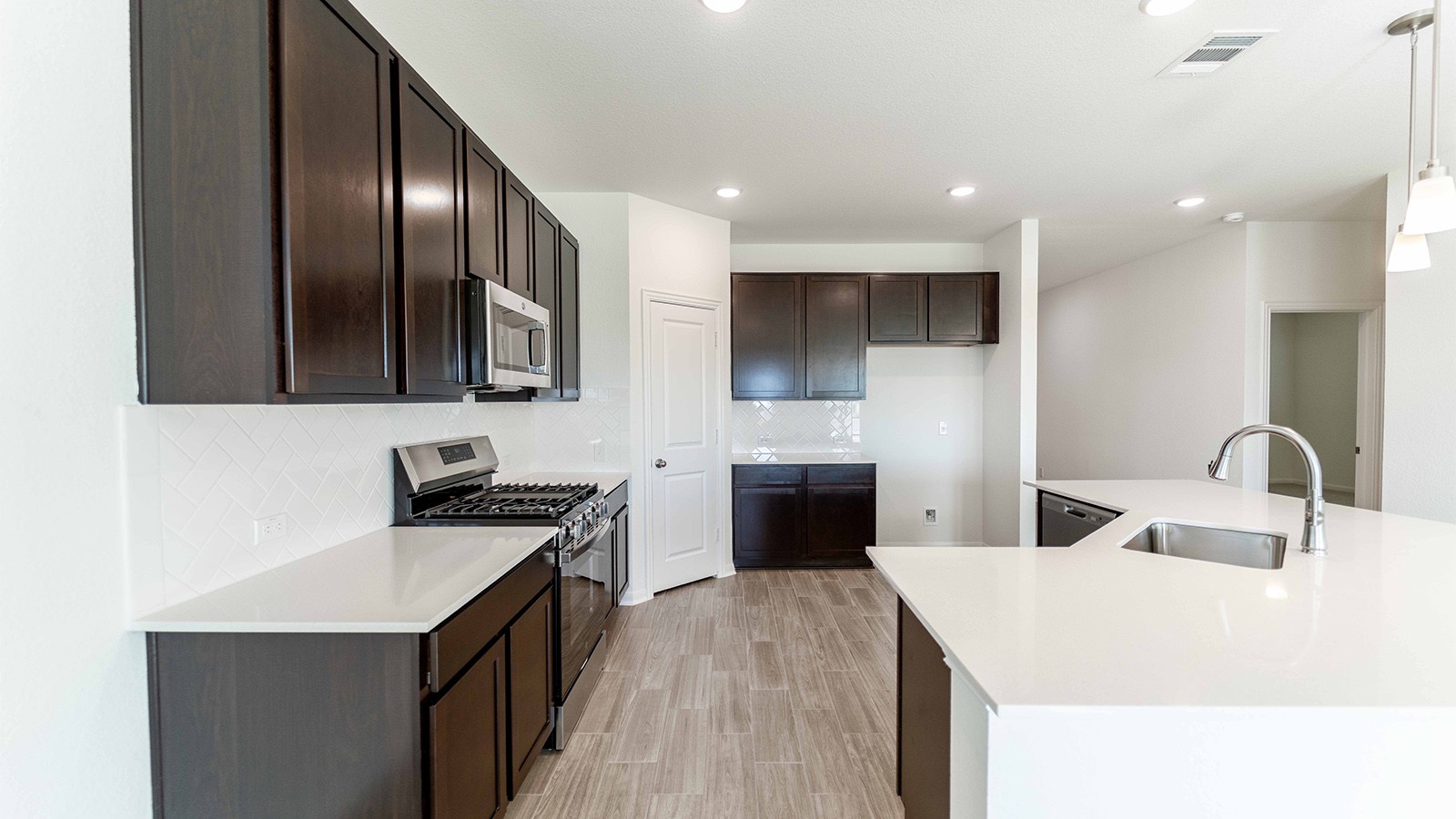 13613 Endless Narrow Lane Elgin, TX 78621 - Photo 4 of 16 a kitchen with granite countertop a stove top oven a sink dishwasher and wooden cabinets