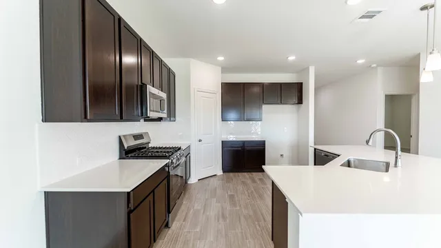 a kitchen with granite countertop a stove top oven a sink dishwasher and wooden cabinets