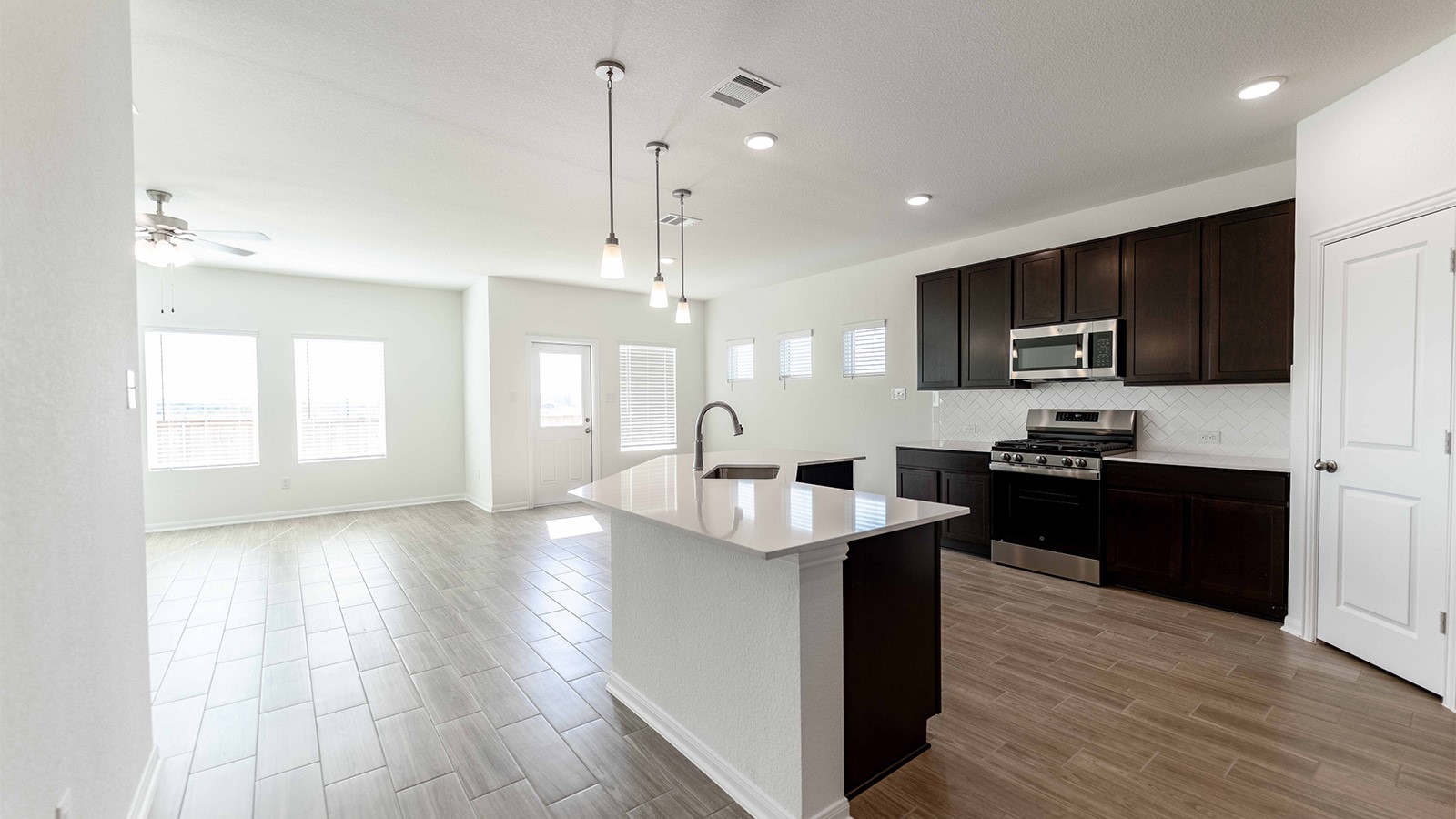 13613 Endless Narrow Lane Elgin, TX 78621 - Photo 7 of 16 a large kitchen with stainless steel appliances granite countertop a sink dishwasher a stove and a refrigerator with wooden floor