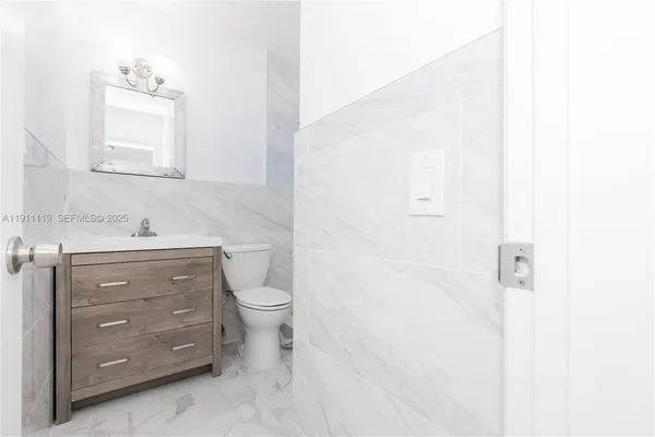 a bathroom with a toilet sink vanity and mirror