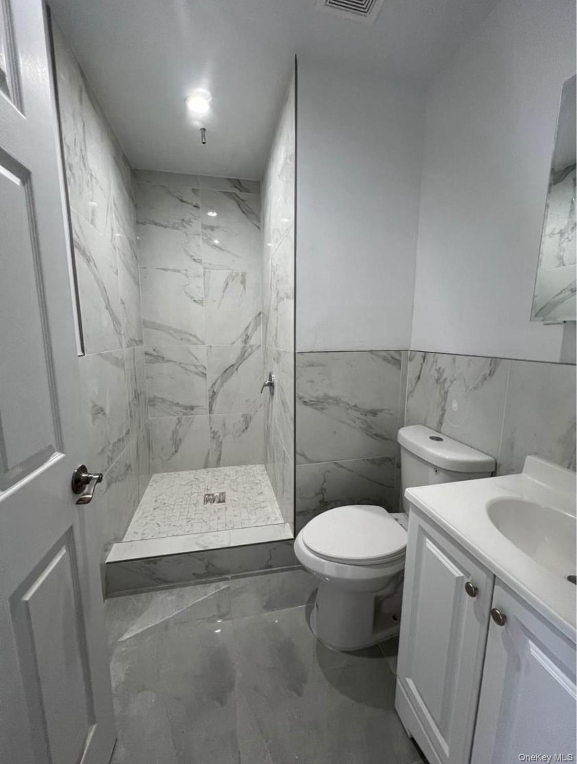 718 Rosedale Avenue Bronx, NY 10473 - Photo 3 of 9 Bathroom with marble look tiles, vanity, a marble finish shower, tile walls, and wainscoting