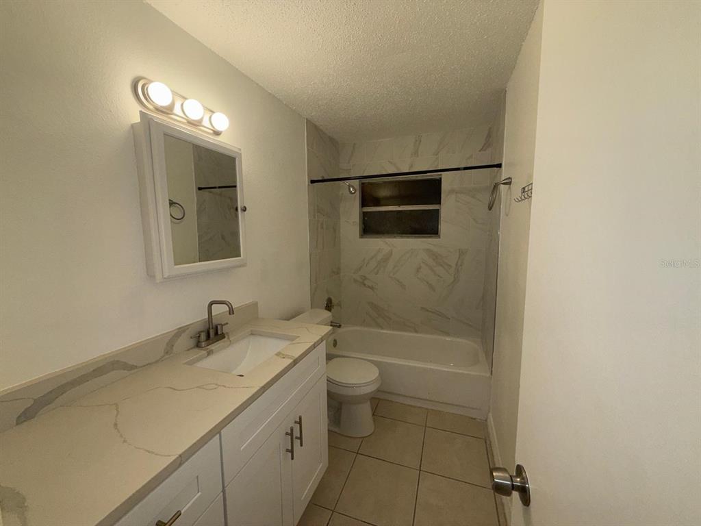 719 Michigan Court, Unit 3 St. Cloud, FL 34769 - Photo 12 of 17 a bathroom with a sink a toilet a shower and a mirror