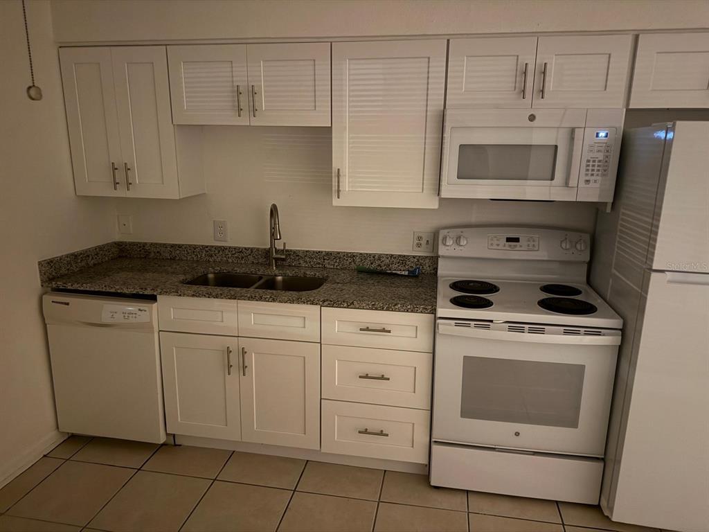 719 Michigan Court, Unit 3 St. Cloud, FL 34769 - Photo 7 of 17 a kitchen with white cabinets and white appliances