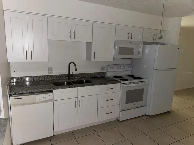 a kitchen with granite countertop white cabinets and white appliances