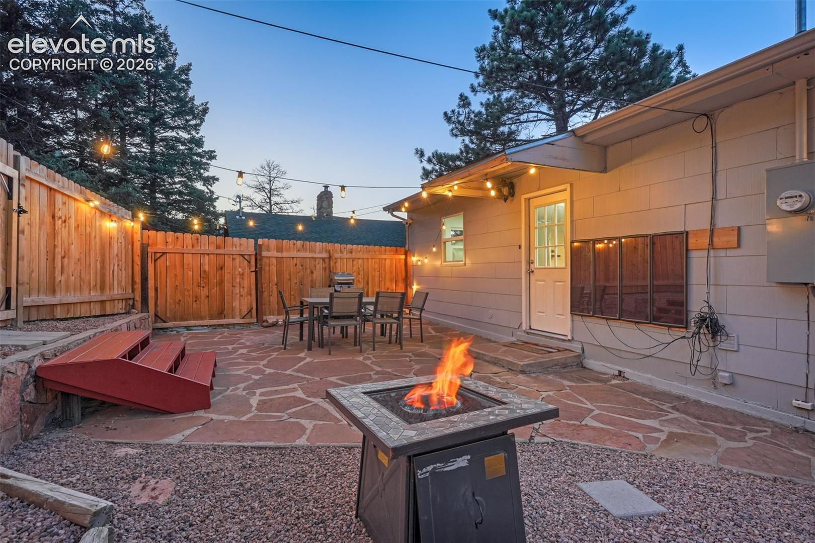 9955 Mesa Road Cascade, CO 80809 - Photo 4 of 41 Flagstone patio with a natural wood fence and exterior lighting