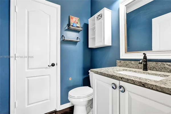 a bathroom with a granite countertop sink toilet and mirror