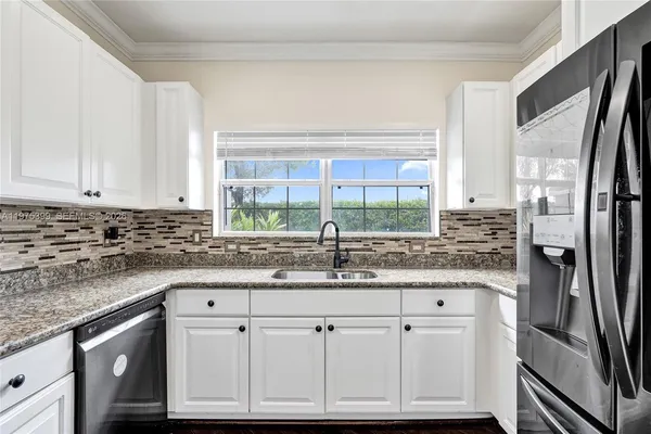 a kitchen with granite countertop a sink stainless steel appliances and cabinets