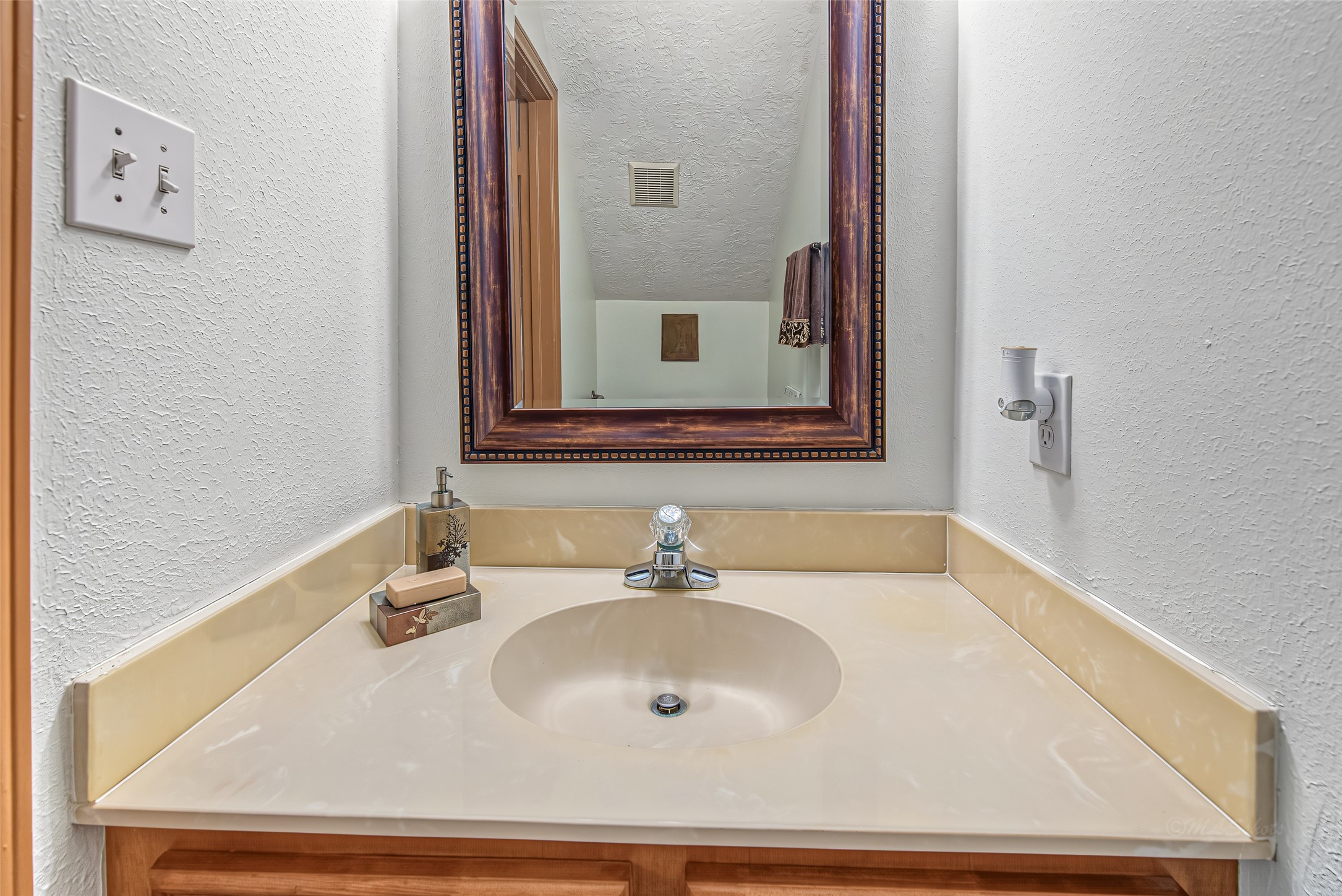 1345 Peach Ridge Road Brookshire, TX 77423 - Photo 26 of 50 Conveniently located for guests, this elegant powder room features a smooth cultured marble vanity top with an integrated sink and a matching full-length backsplash. Set against clean, light walls, the space is highlighted by a rich, dark-stained framed mirror with decorative bead molding that adds a touch of classic warmth.