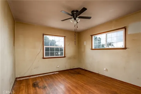 a view of an empty room with a window and wooden floor