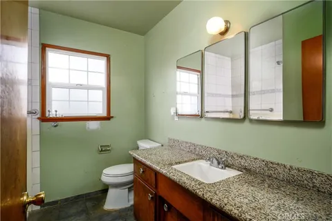 a bathroom with a granite countertop toilet sink and mirror