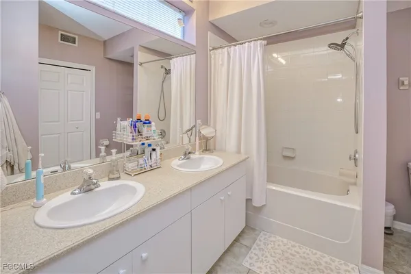 a bathroom with a sink double vanity granite tub shower and a mirror