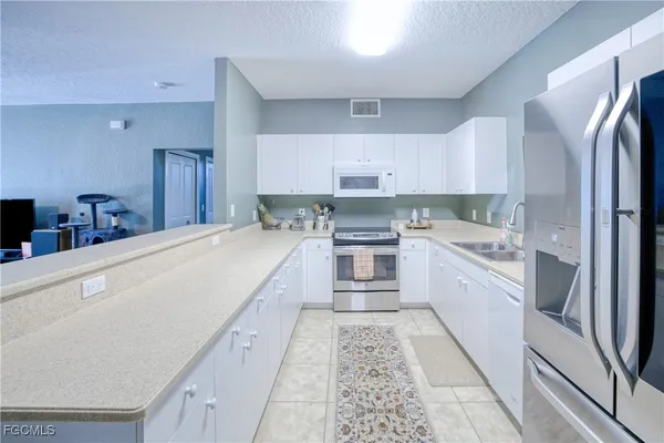 a large white kitchen with stainless steel appliances cabinets a sink and a stove