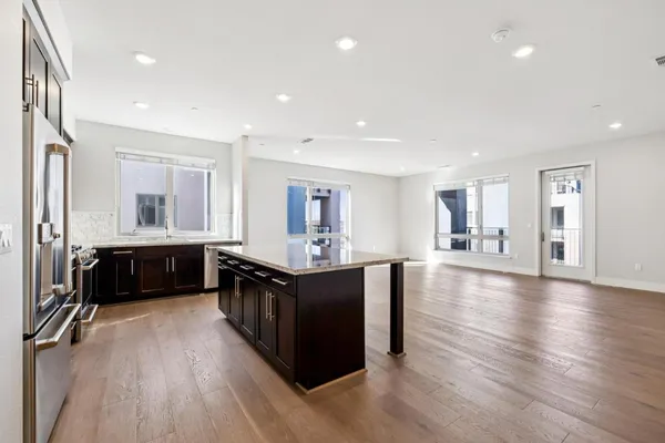 a large white kitchen with wooden floor and a large window