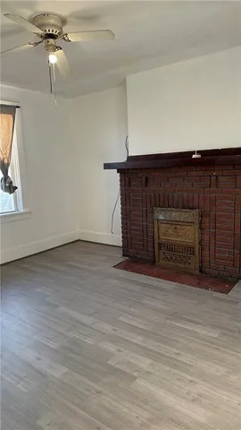 an empty room with wooden floor ceiling fan and windows